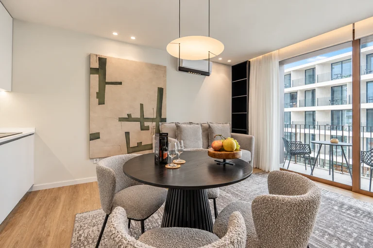 Detalhe da zona de jantar, com a sala e a varanda ao fundo